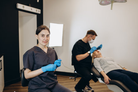 Assistant in dentist cabinet during elderly woman oral hygiene check up sitting on chair. Senior woman talking with medical nurse in stomatology office about teeth problem.の写真素材