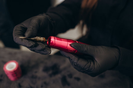 Permanent makeup machines in cosmetologist hand. Hands holding tattoo machine.permanent make-up tattoo concept.の写真素材
