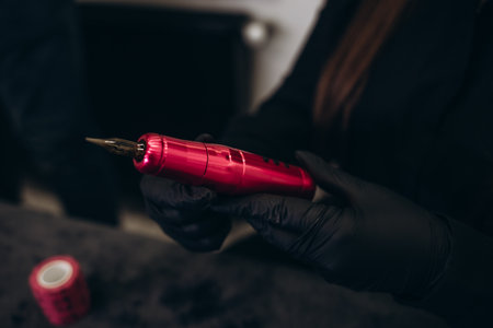 tattoo machine in female hands in black gloves.tattoo permanent makeup beauty workshopの写真素材