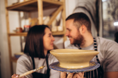 own cup. Young couple feeling satisfied while leaving pottery master class with their own cupの写真素材