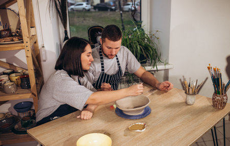 Young man and young woman examining painted pottery in workshopの写真素材
