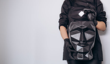 a woman in black gloves holds a sculpture of a head and a can of nail polishの写真素材