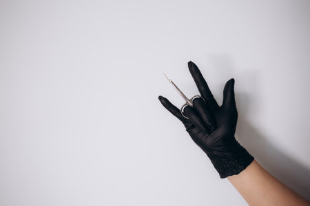 a woman in black gloves holds manicure scissorsの写真素材