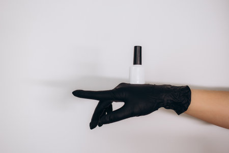 a woman in black gloves holds a can of nail polishの写真素材
