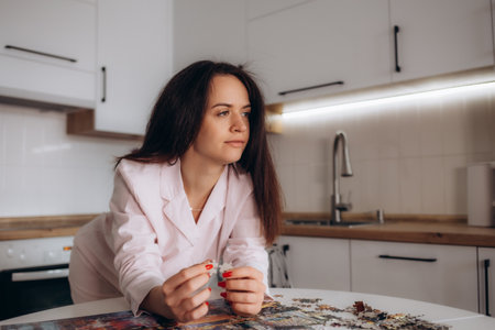 A woman in pajamas is doing puzzles in the kitchenの写真素材