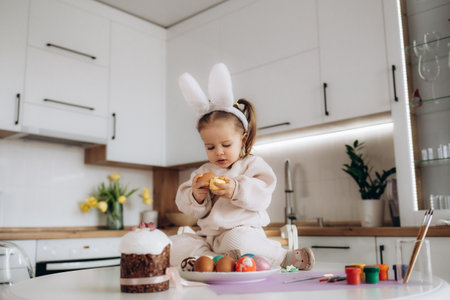 Child paints easter egg. Creativity with children. girl's hands with eggs on the background of a table with paints, brushes, eggs, holiday flags.do-it-yourself. Handicrafts and crafts for Easter. DIYの写真素材