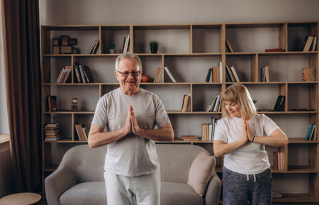 Mature couple practicing yoga and performing warrior yoga pose together.の写真素材