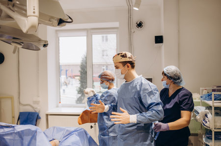 Doctor, uniform and surgeon prepare for surgery, operation or medical healthcare. Nurse helping worker with safety clothing in emergency operating room, hospital and wellness support, theater or riskの写真素材