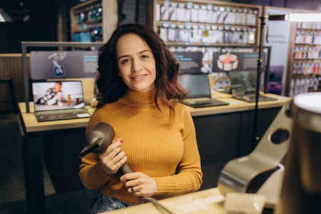 Beautiful woman in the store is testing a hairdryerの写真素材