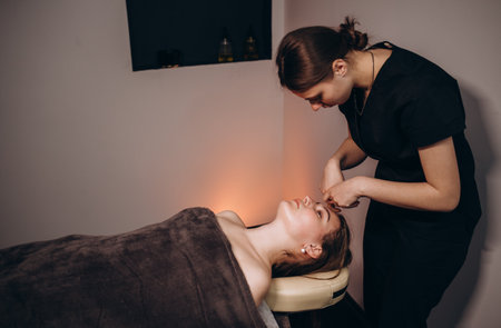 face massage. Close-up of young woman getting spa massage treatment at beauty spa salon.Spa skin and body care. Facial beauty treatment.Cosmetology.の写真素材