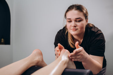 The masseur massages the feet of a young woman. Healing body massage at the medical center.の写真素材