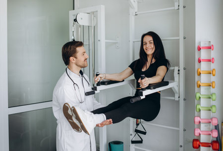 Young fitness woman doing kinesiotherapy rehabilitation exercise with personal rehabilitation specialist in the gym.の写真素材