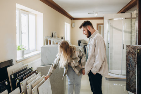 Beautiful young couple choosing ceramic tiles for their house repairment in the building shopの写真素材