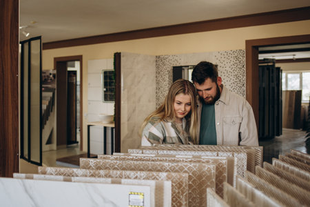 Beautiful young couple choosing ceramic tiles for their house repairment in the building shop.の写真素材