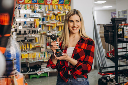 Beautiful smiling saleswoman is selling a drill at hardware store. All potential trademarks are removed.の写真素材