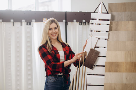 Experienced salesman offering laminated flooring to customer in shop of building materialsの写真素材