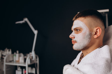 Portrait of man with clay facial mask in beauty spa.の写真素材