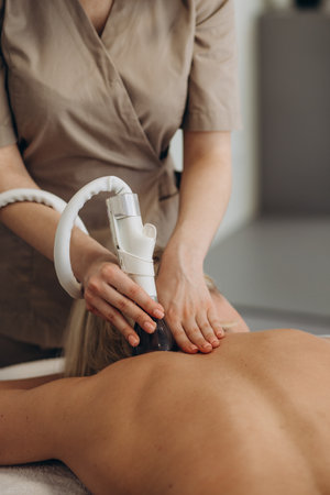 The girl in the spa salon receives a back and neck massage, lies in the cosmetology table, relaxed and enjoys the processの写真素材