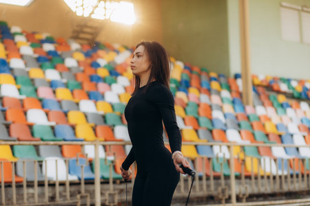 Young woman skipping rope during sunny morning on stadium trackの写真素材
