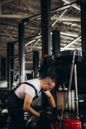 Happy young mechanic draining engine oil at an auto shop for an oil change.の写真素材