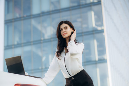 Stylish business female using modern laptop for remote work while walking on the street near office...
