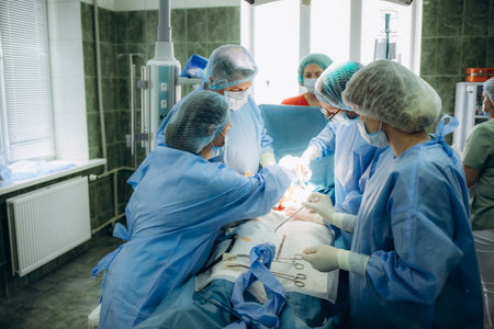 surgeons perfoming surgery operation of abdominal cesarean section during child birth delivery at clinic operating room.の写真素材