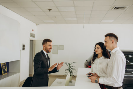Portrait of mature bearded businessman talking to sales manager sitting across desk in car dealership showroom, copy spaceの写真素材