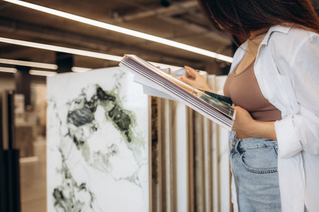 a woman looks at a catalog of tiles in a store.の写真素材