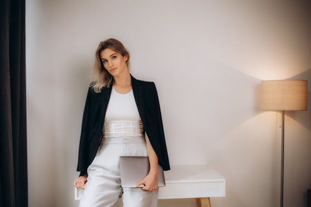 blonde in a black jacket with a laptop in the office.の写真素材