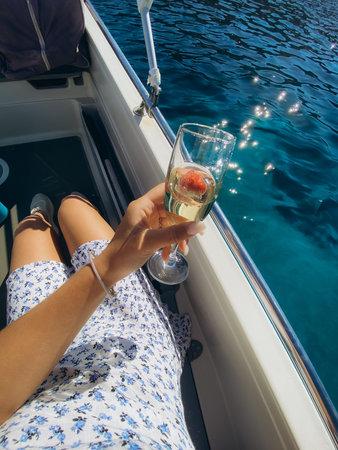 Hands holding glasses with champagne over the sunset sky. Romantic luxury evening on cruise yacht....