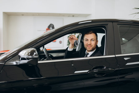 Smiling, friendly car sellers standing in car salon with arms crossed and announcing retail. High...