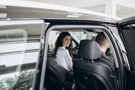 auto business, car sale, technology and people concept - happy couple with car dealer in auto show or salon. High quality photoの写真素材