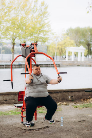 a fat man does sports outdoors on exercise machines