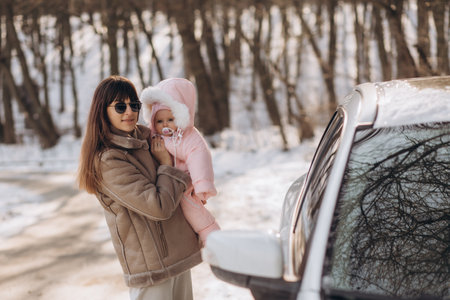 mother and daughter are standing near the car in the winter forestの写真素材