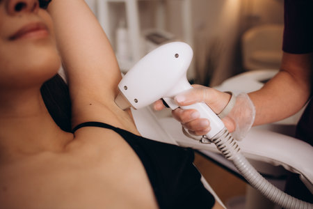 Body care concept. Laser hair removal. Young Caucasian woman in safety glasses lies on the sofa, female cosmetologist doing laser hair removal in a beauty salon. High quality photoの写真素材