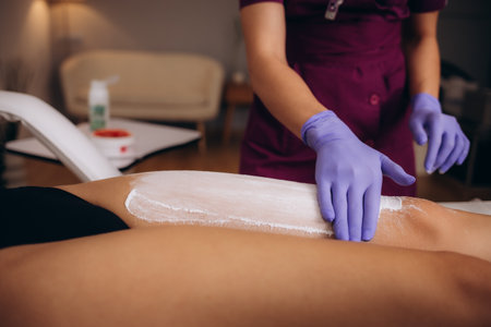 a cosmetologist rubs a leg with talcum powder in front of a sugar bowlの写真素材
