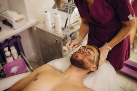 Cosmetologist applying mask on client's face in spa salon. High quality photoの写真素材