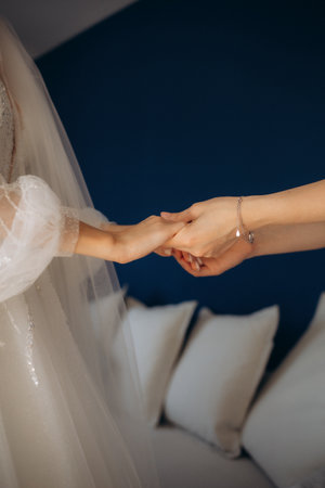 Hands of mother and bride daughter in white wedding dress and gloves in her arms, close-up of family love and tenderness. High quality photoの写真素材