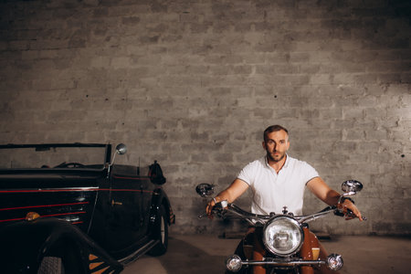 A man sits on a retro motorcycle in his garageの写真素材