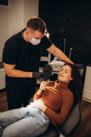 Doctor is examining beautiful young woman's face using a special equipment. High quality photoの写真素材