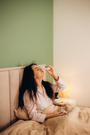 Bless you. Negative female sitting under soft blanket and dropping her nose. High quality photoの写真素材