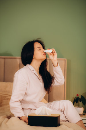 Young woman with nosebleed and tissue at home. High quality photoの写真素材