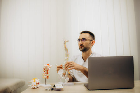Portrait of a good looking young orthopedist with a beard working in his office and taking notes...