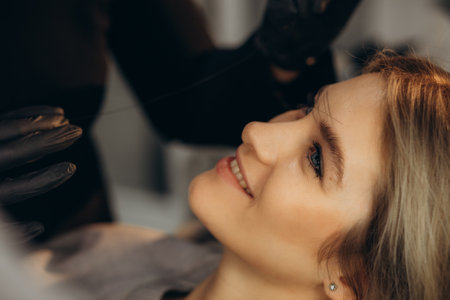 Marking of eyebrows. Permanent brow makeup. Markings with white paste and measuring ruler. Permanent make up artist in black gloves. High quality photo. High quality photoの写真素材