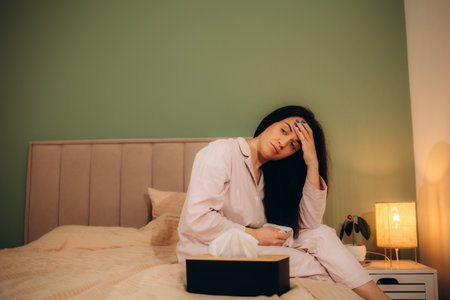 Sick desperate woman has flu. Rhinitis, cold, sickness, allergy concept. Asian sick woman has runnning nose, rubs nose with handkerchief. Sneezing female. Brunette sneezing in a tissue. High quality photoの写真素材