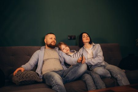 a family with a cat is watching TV sitting on the sofa