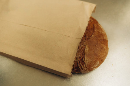 Paper bag with sesame bun on white background, top view. Space for text