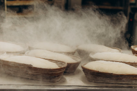 Cooking sourdough homemade bread. Sieving flour over raw bread dough on table, dark background, selective focus.の写真素材