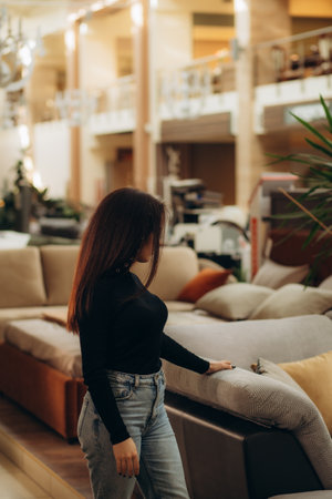 Joyful woman in furniture center chooses best sofa for her apartmentの写真素材