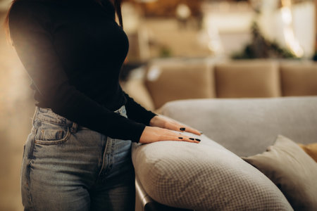 A woman tries the textile of a sofa in a store with her handの写真素材